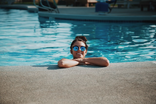 pool design - woman in pool with sunglasses smiling at camera