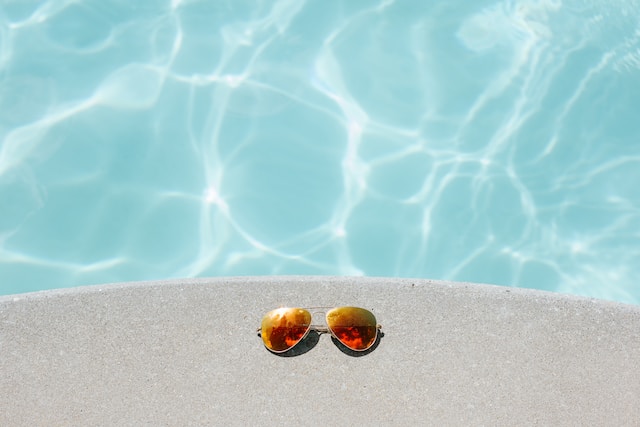 Pool Renovation - Orange sunglasses sitting on the concrete next to a swimming pool